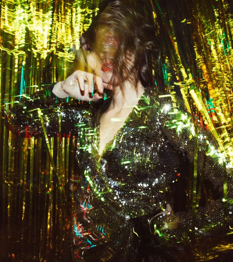 Woman in a dynamic yoga pose against a dark background with gold light.